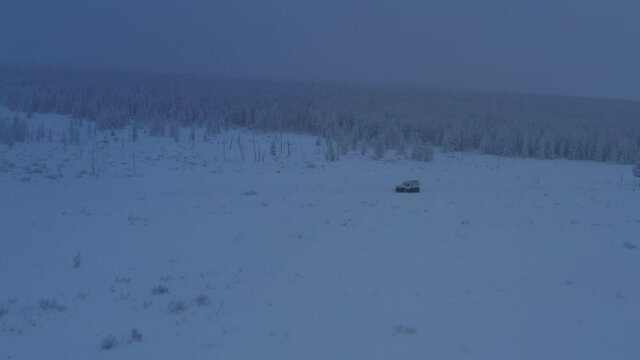The six-wheel Trekol all-terrain vehicle rides through the snow-covered tundra in the sunset light
