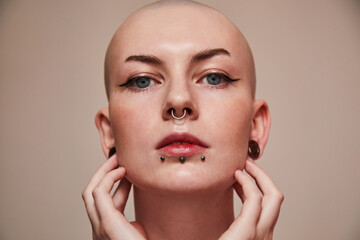 Short haired naked woman with piercing at her face looking straight while posing