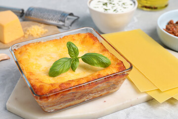 Tasty cooked lasagna in baking dish on light table