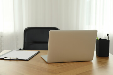 Stylish workplace with modern laptop near window in room. Interior design