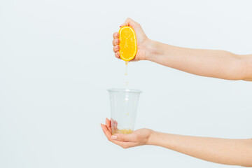 Woman's hand squeezing orange juice from fresh orange