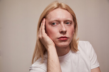 Man with feminine appearance looking away with serious expression while posing