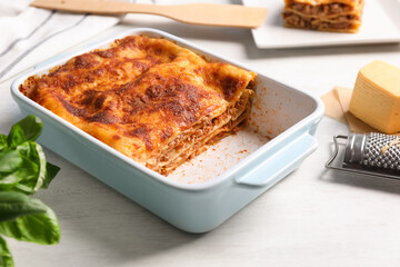 Delicious lasagna in baking dish on white table