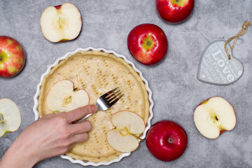 preparation of dough in the form for apple pie, top view on gray concrete background