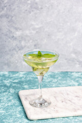 A glass of mojito cocktail with lime and mint and kiwi