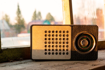 Vintage portable radio receiver stands on a dusty windowsill against the background of an unwashed...