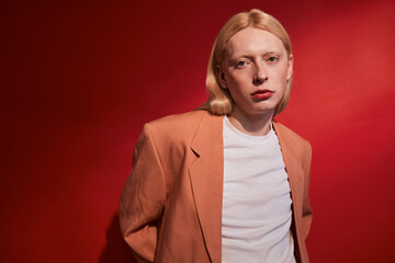 Long haired man with feminine features wearing stylish jacket looking at the camera