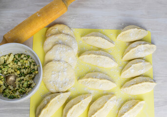 Process of making homemade pies with egg and onions, rolling pin for dough, on the kitchen table. Concept of making pies at home. Top and side view. Selective focus.