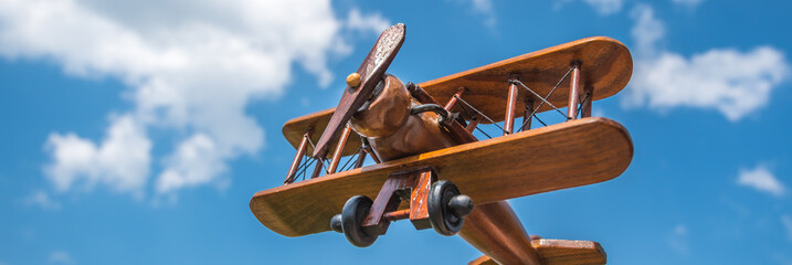 The hand hold a wooden plane on the background of the cloud