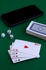 online poker games. four aces with dice and phone in casino. playing cards with blue deck on the green table. combination of cards on a green casino desk background.copy space.
