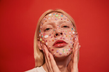 Long haired guy with rhinestones at his face holding his hands near his head