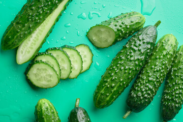 Set of fresh whole and sliced cucumbers on a green background with water drops. Garden cucumber wallpaper backdrop design