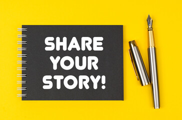 On a yellow background lies a pen and a black notebook with the inscription - Share Your Story