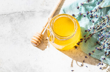 Flowing honey from wooden dipper in a glass jar. Organic honey dipping from the wooden honey spoon. Lavender honey