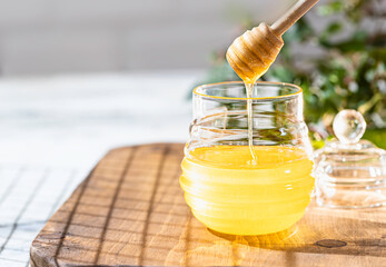 Flowing honey from wooden dipper in a glass jar. Organic honey dipping from the wooden honey spoon.