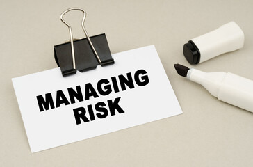 On a gray background lies a marker and a business card with the inscription - MANAGING RISK