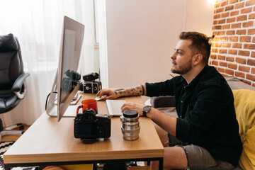 Yung caucasian man with photo camera and computer