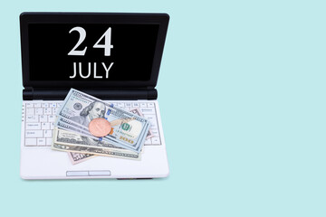 Laptop with the date of 24 july and cryptocurrency Bitcoin, dollars on a blue background. Buy or sell cryptocurrency. Stock market concept.