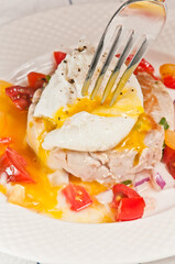 Tuna with Poached Egg and sliced Cherry Tomato and onion Salsa and a fork beginning to pierce the egg yolk