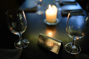 Sign reserved on table with candle burning in background and served table