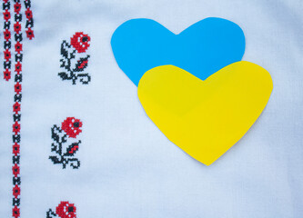 blue and yellow paper hearts on a fabric with an embroidered traditional ornament