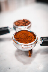 Ground black coffee pouring into a portafilter with a grinder