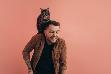 Man laughing while his striped cat sitting at his shoulder