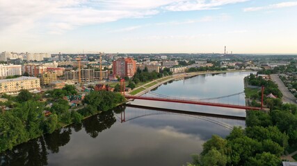 Fototapeta na wymiar Suspension bridge in the city of Penza, Russia. Red Suspension Metallic Bridge. Red suspension bridge over the river.
