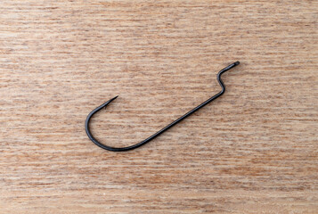 Single offset worm bait hook on a wood background.