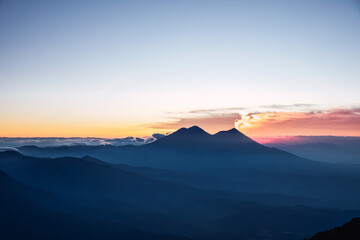 Vista panorámica al Volcán Acatenango el camellón del Volcán de Fuego y una erupción al amanecer