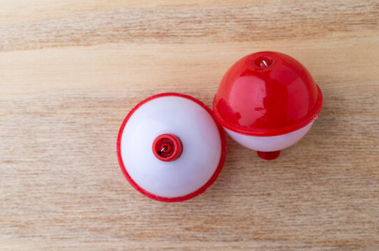 Two red and white plastic fishing bobbers top view