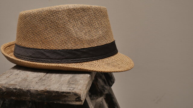 Sombrero de paja sobre escalera. Colores primarios: Marr&oacute;n, negro y blanco.