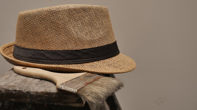 Sombrero de paja y brocha sobre escalera. Colores primarios: Marr&oacute;n, negro y blanco.