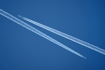 Two planes pass by in the blue sky 