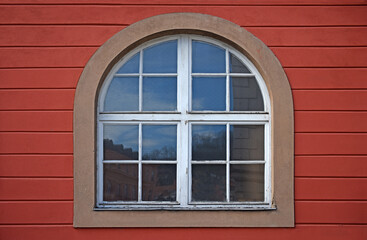 Old wooden window with arch on red wall