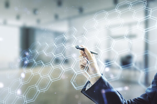 Man hand with pen draws abstract virtual wireless technology hologram with hexagon on blurred office background. Big data and database concept. Multiexposure