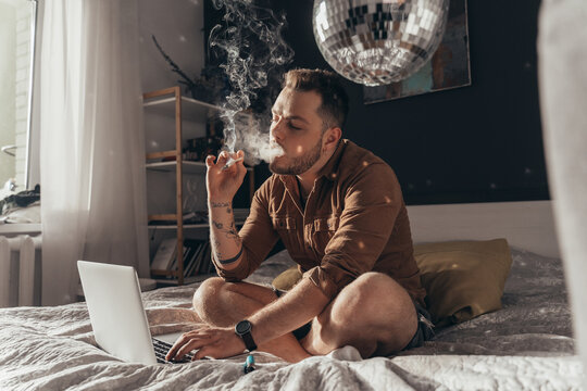 Man blowing out puffs of smoke and smoking weed hand rolled cigarette