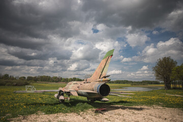 old vintage reactive airplane, plane in the field with dandelions, cloudy dramatic sky in the middle of early may day