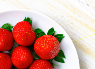 Ripe Strawberries in a White Plate. Fresh Juicy Strawberries with Leaves. Summer Berries Background.