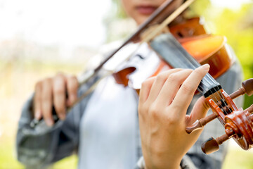 Close-up portrait of Young Asia woman music violinist hand play violin, relax in the garden with peace of mind