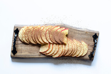 Apple slices in cocoa. On a wooden tray. On white background.