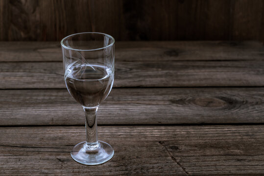 Glass of vodka on an old wooden table. Angle view
