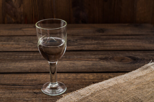 Glass of vodka with piece of cloth on an old wooden table. Angle view