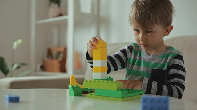 Child sneezing playing with colorful building plastic blocks constructor at home