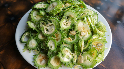 Lots of Chopped Bitter Gourd on Ceramic plate on wooden table at home in Dhaka, Bangladesh