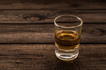 Glass of tequila on an old wooden table. Close up view