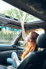 woman with an open window in the front seat of a car gesturing with her hands interior salon fellow traveler