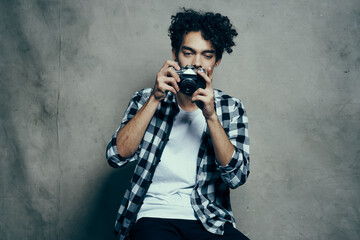 guy with a camera in his hands on a gray background indoors hobby plaid shirt model