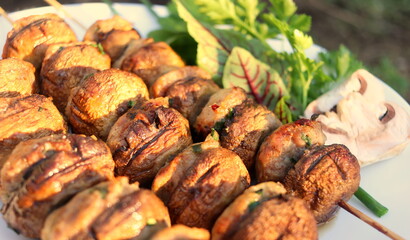 Champignon mushrooms baked on the grill on open coals on a summer day close-up, delicious and healthy food, eating for a picnic.