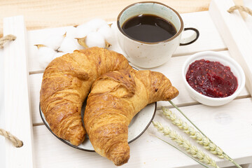 A cup of coffee and croissants with jam. A breakfast idea.